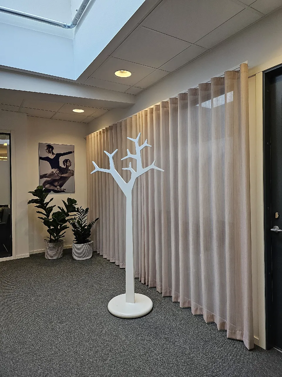 Entré med klädhängare och ljusa gardiner längs väggen