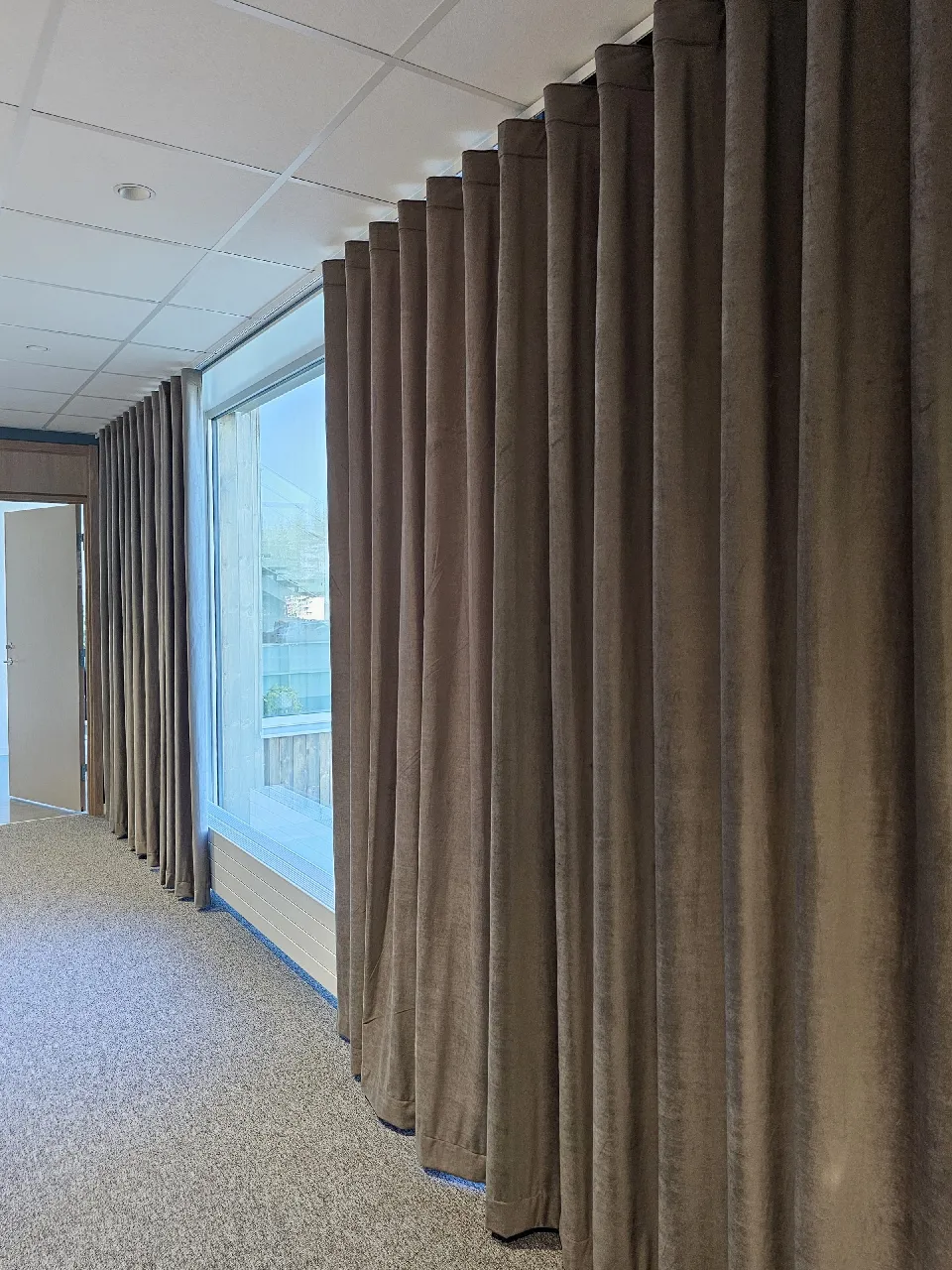 Mörk gardin vid ett fönster i en kontorslokal