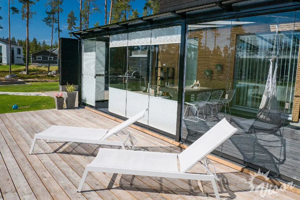 Inglasad altan sedd utifrån, med plisségardiner bakom glaset
