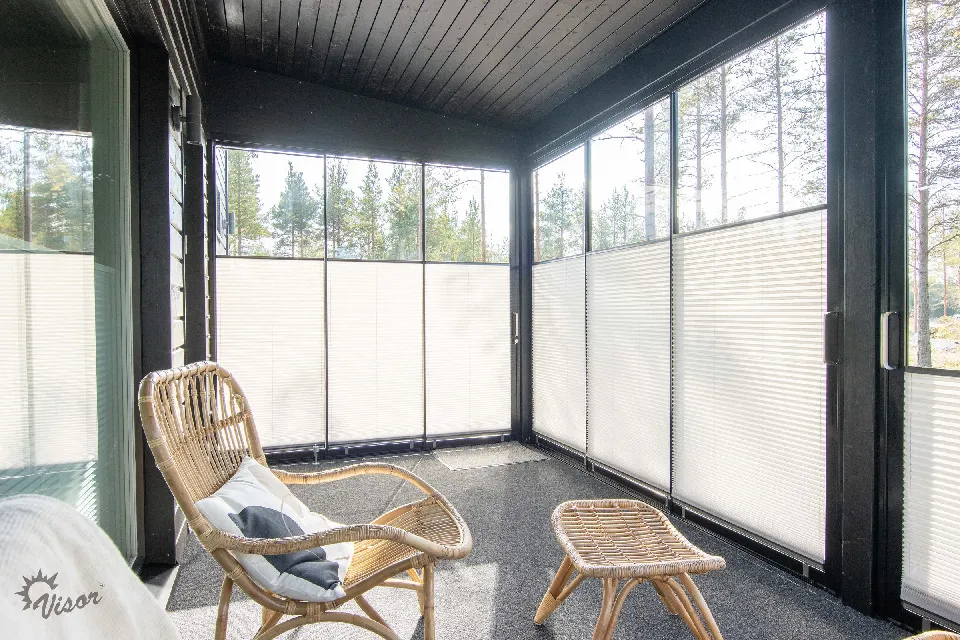 Inglasad altan med korgfåtölj och plisségardiner i hörnet