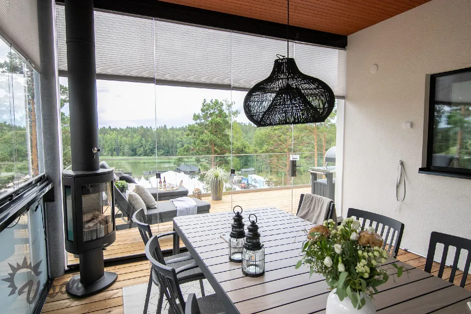 Inglasad altan med matbord, kamin och plisségardiner