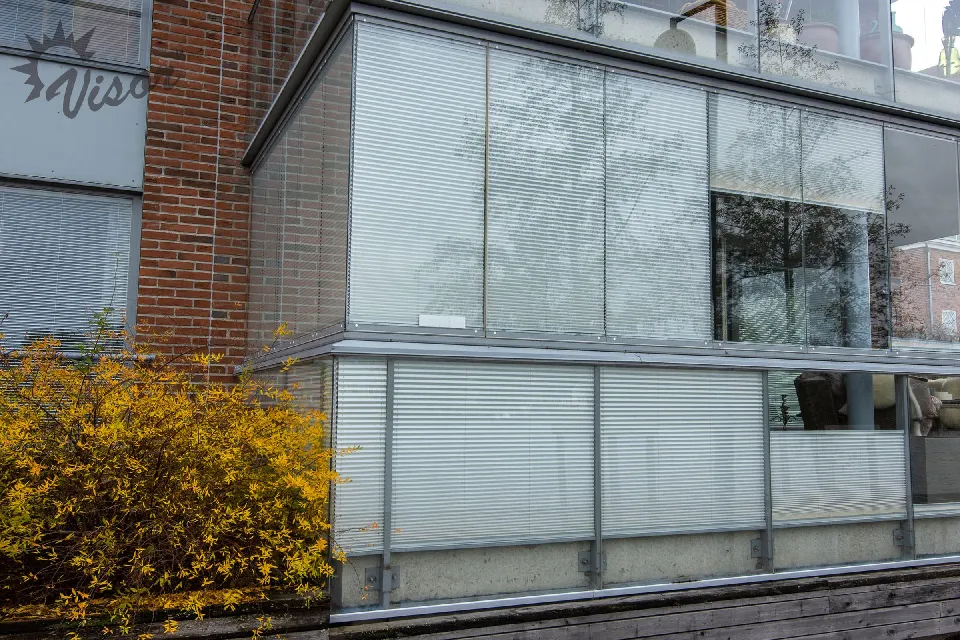 Inglasade balkonger på ett tegelhus med plisségardiner