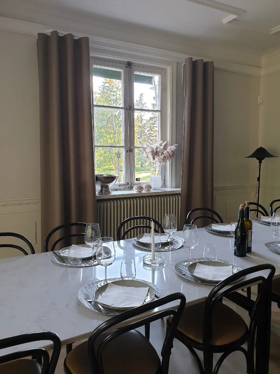 Dukat matbord vid ett fönster med bruna gardiner