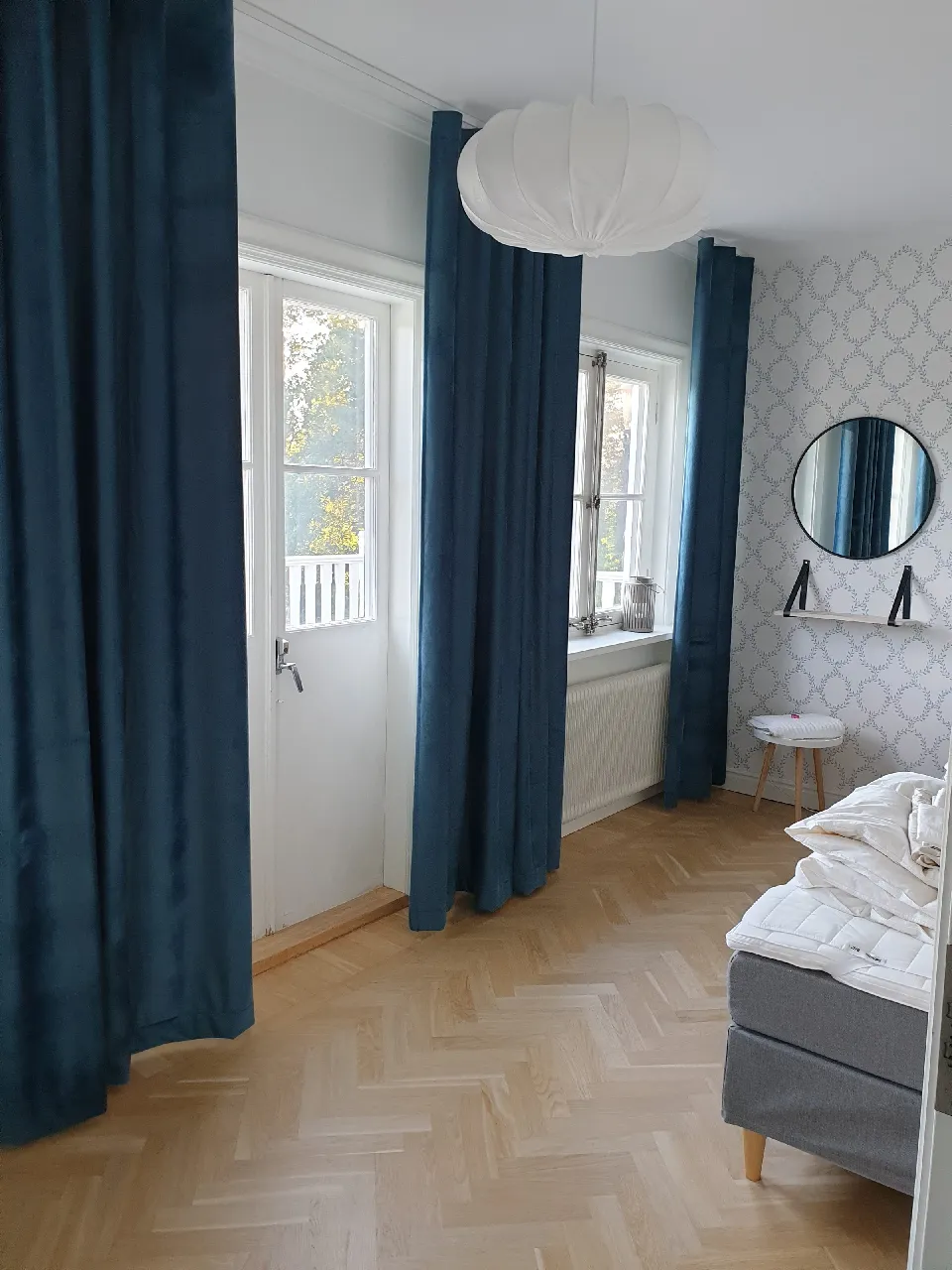 Sovrum med mörkblå gardiner och mönstrad tapet
