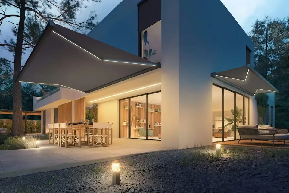 Villa i skymning med terrassmarkiser över uteplats och matplats