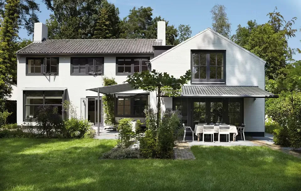 Vit villa med pergolamarkis över uteplatsen