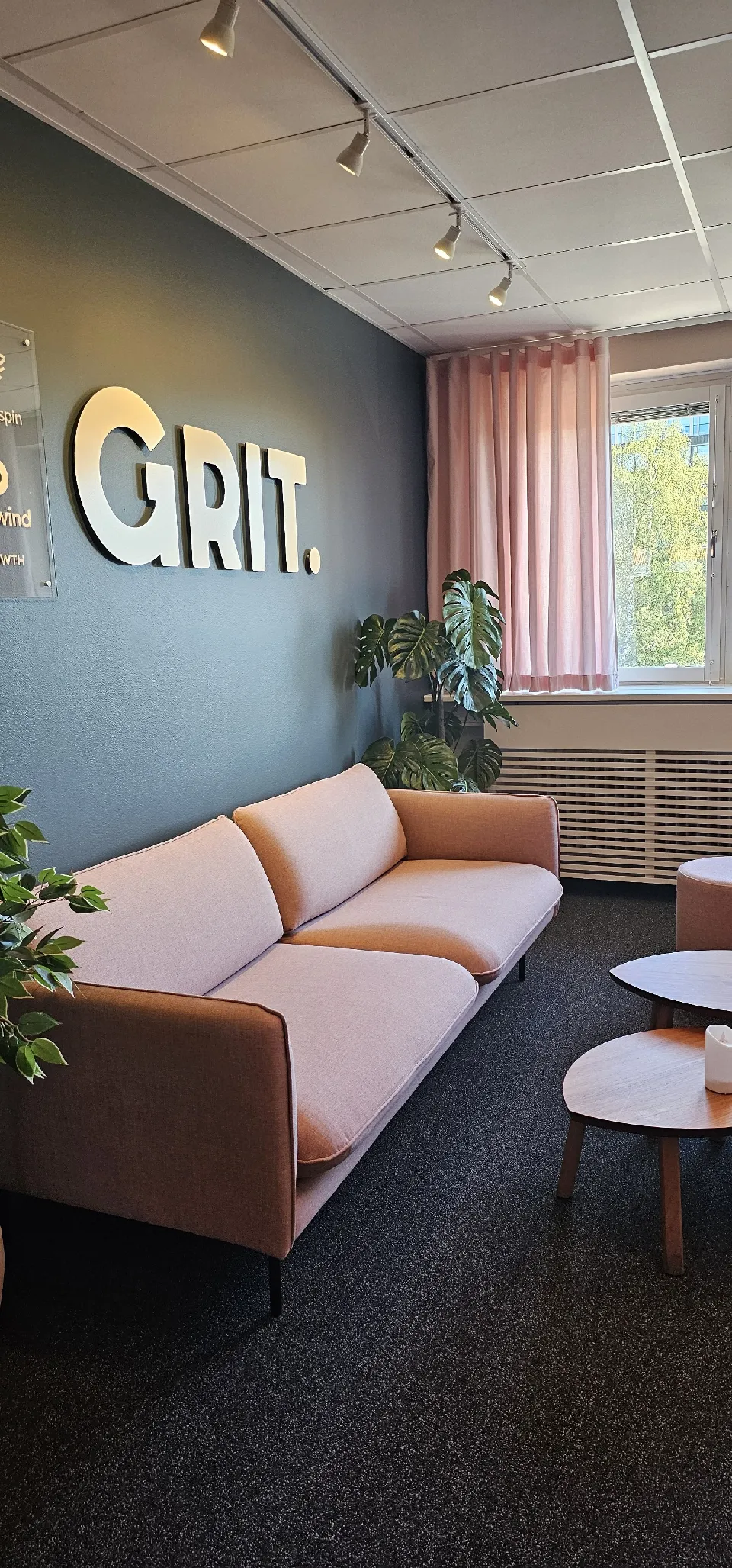 Kontorsrum med soffa och en rosa gardin vid fönstret