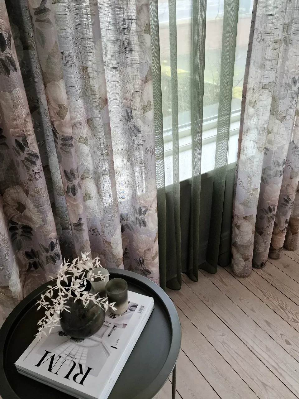 Gardiner i blommönster och grönt vid ett golvfönster
