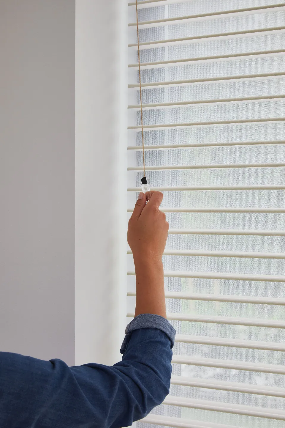Hand som vinklar tyglamellerna i en Silhouette-gardin