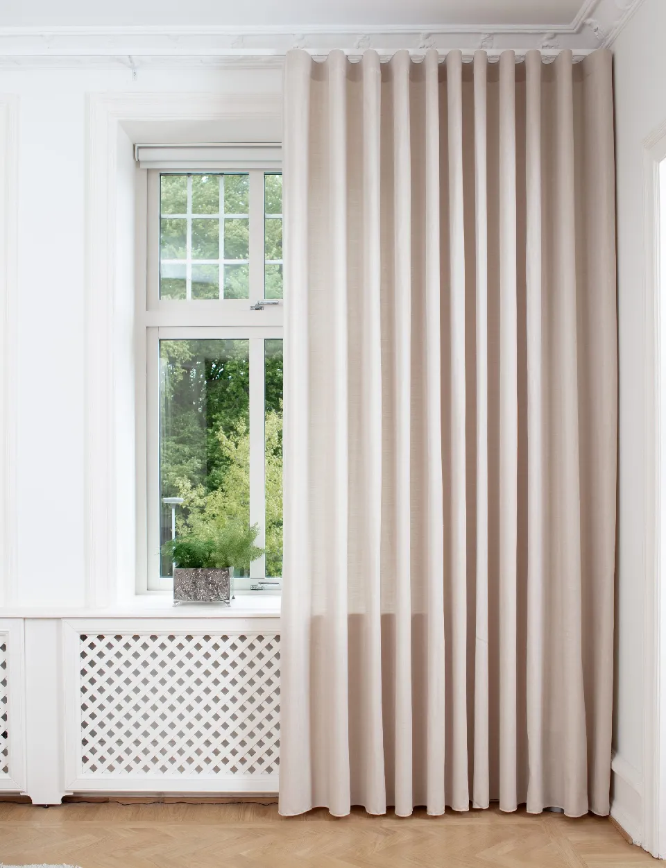 Ljusbeige gardin vid ett spröjsat fönster