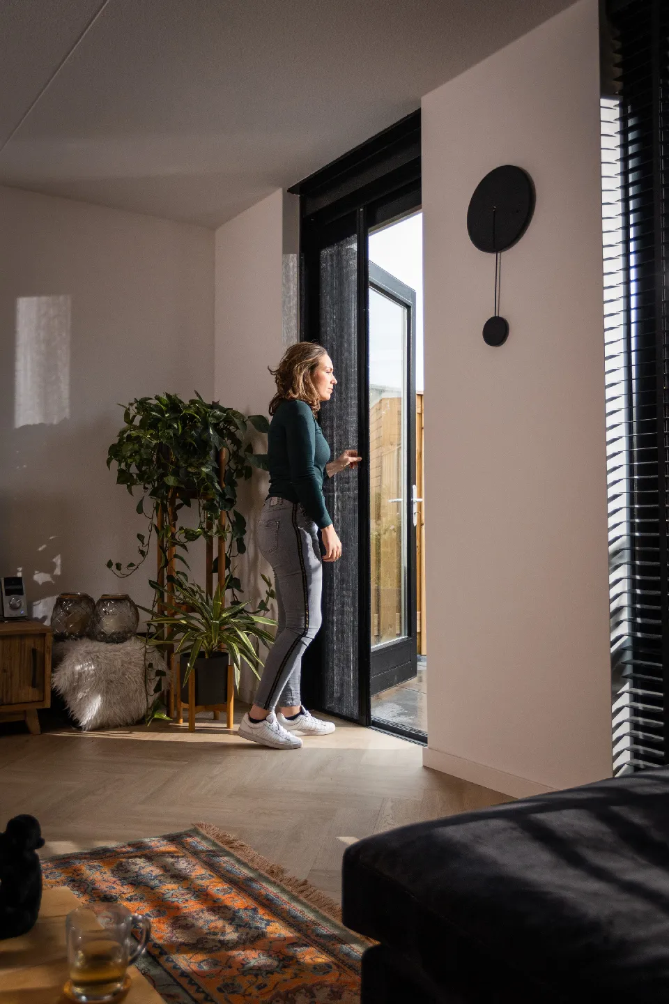 Kvinna på väg ut genom en altandörr med insektsnät