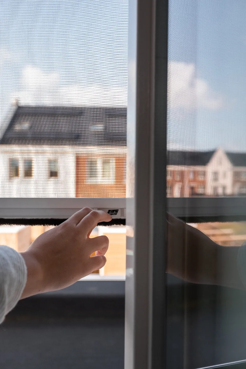 Hand som justerar ett insektsnät i ett fönster