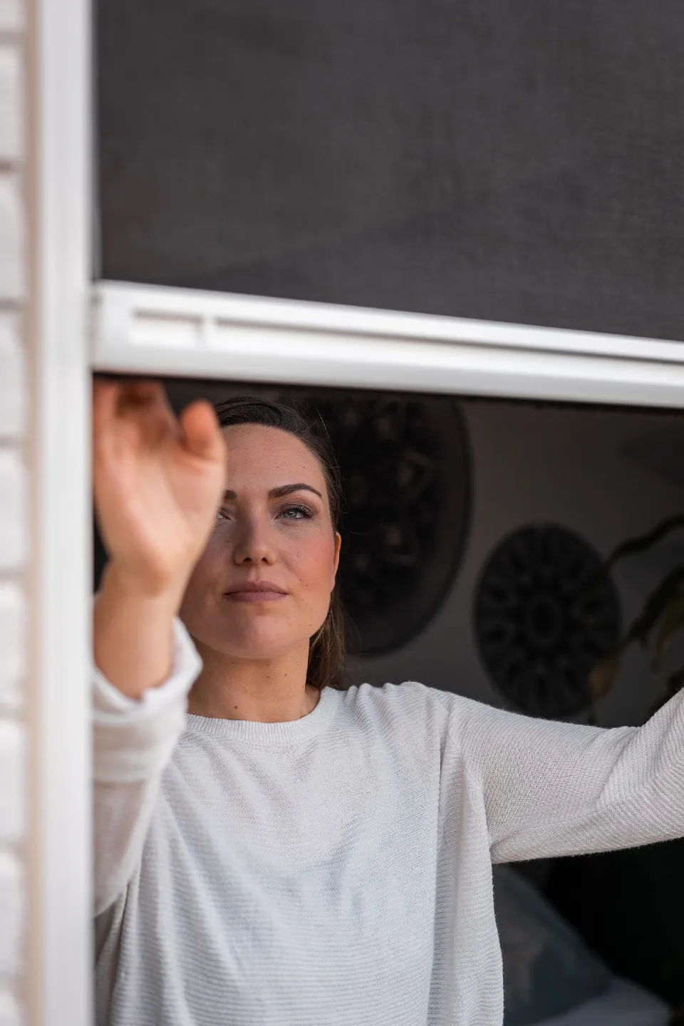Kvinna som sätter fast ett insektsnät i ett fönster