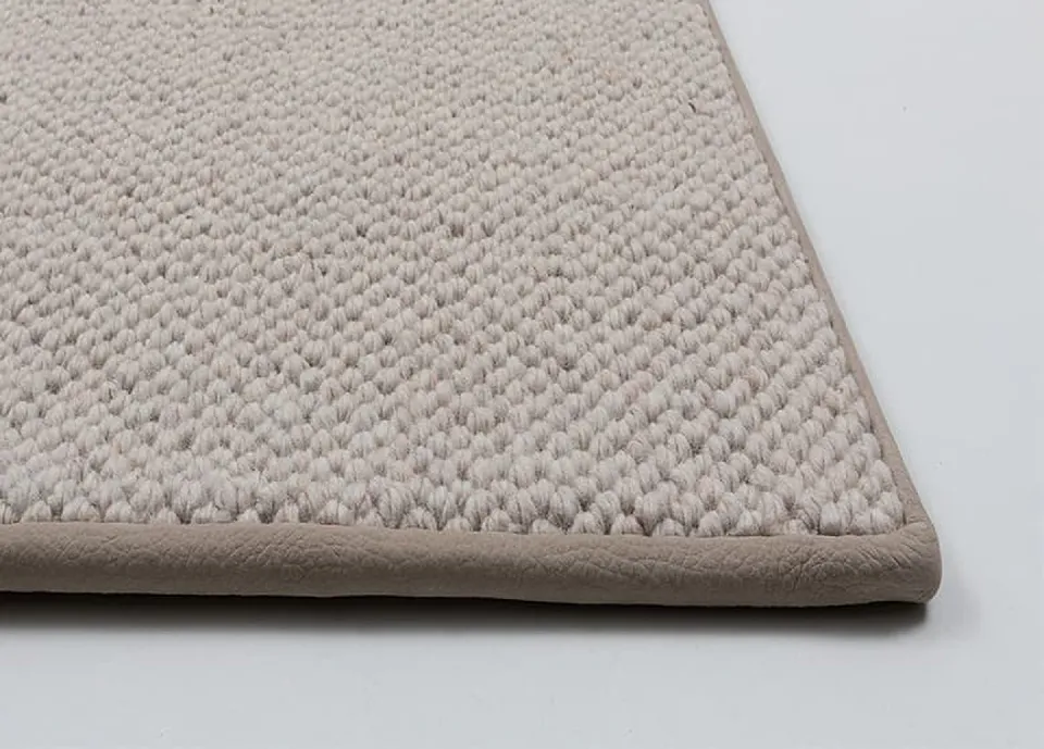 Hörn av en rumsmatta med bubblig vävstruktur i beige