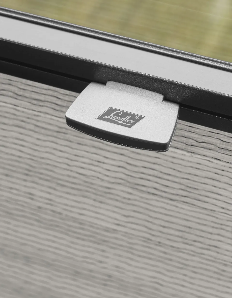 Närbild på plisségardinens överlist med Luxaflex-märkning