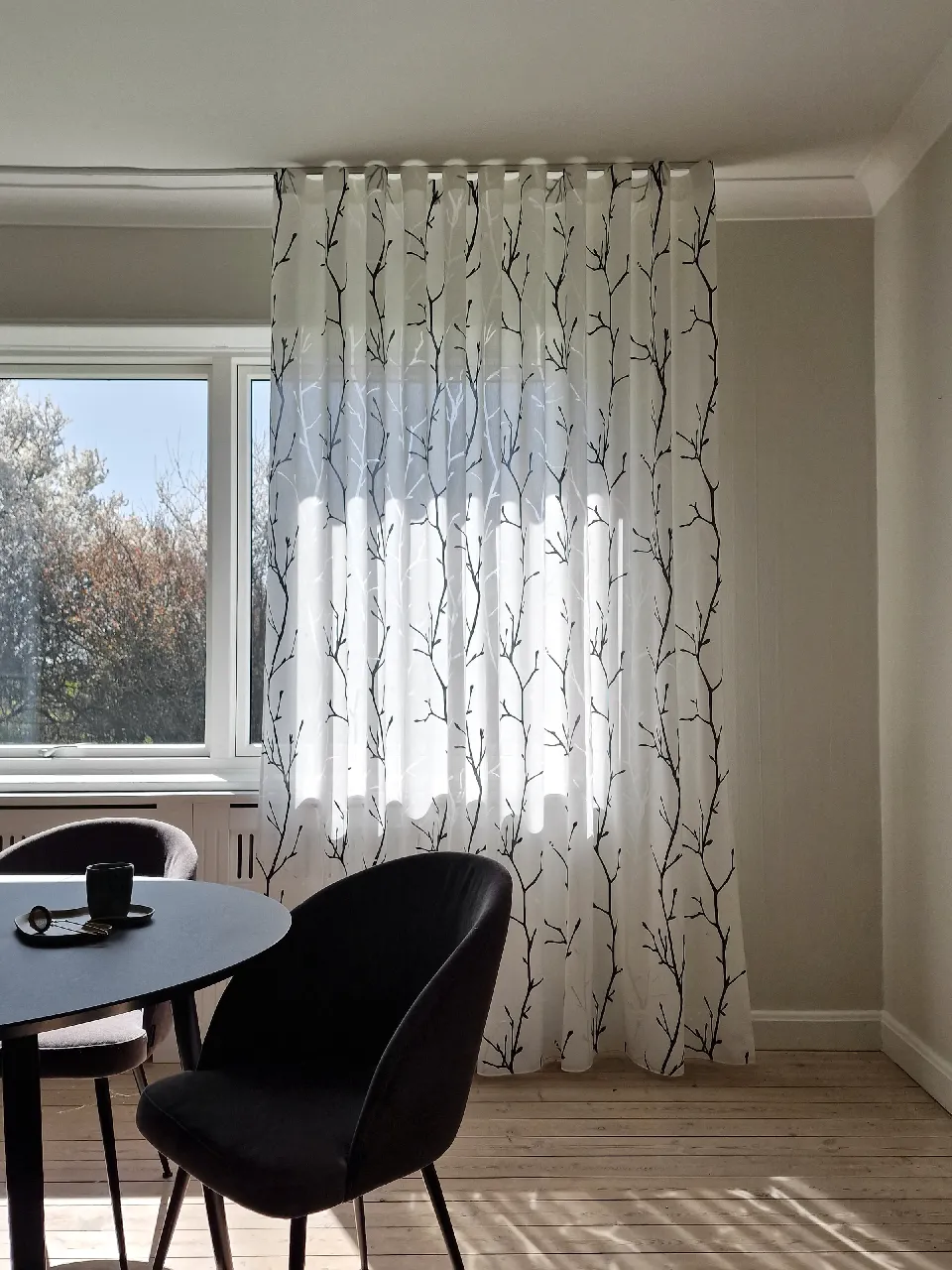 Matplats med gardiner i grenmönster vid fönstret