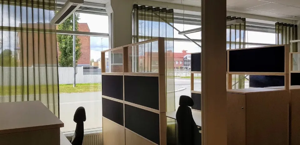 Kontorslandskap med rumsavdelare och gardiner vid fönstren