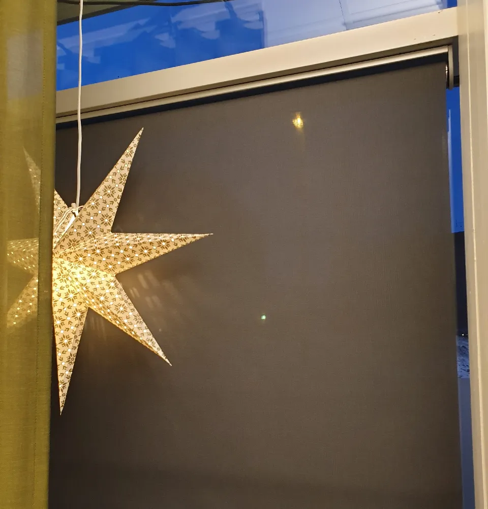 Adventsstjärna framför en gardin i guldton