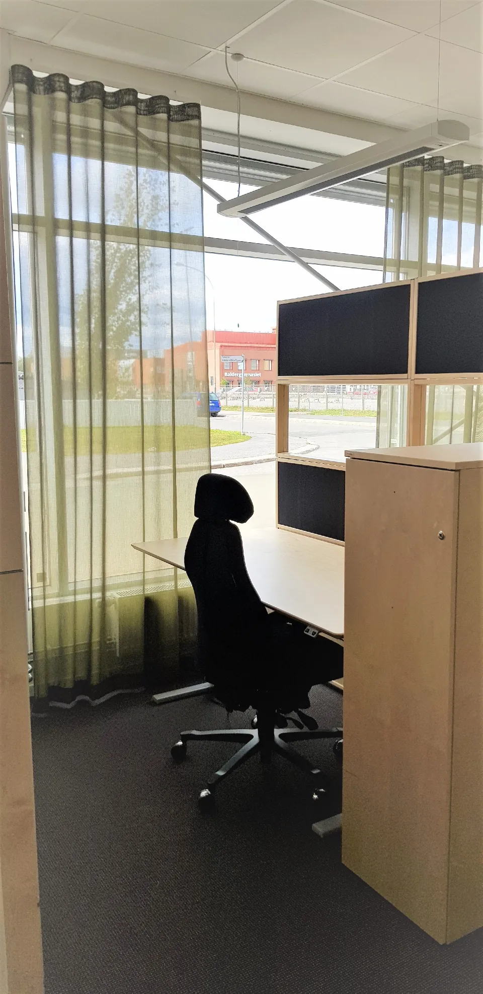 Arbetsplats vid ett fönster med gardiner i guldton