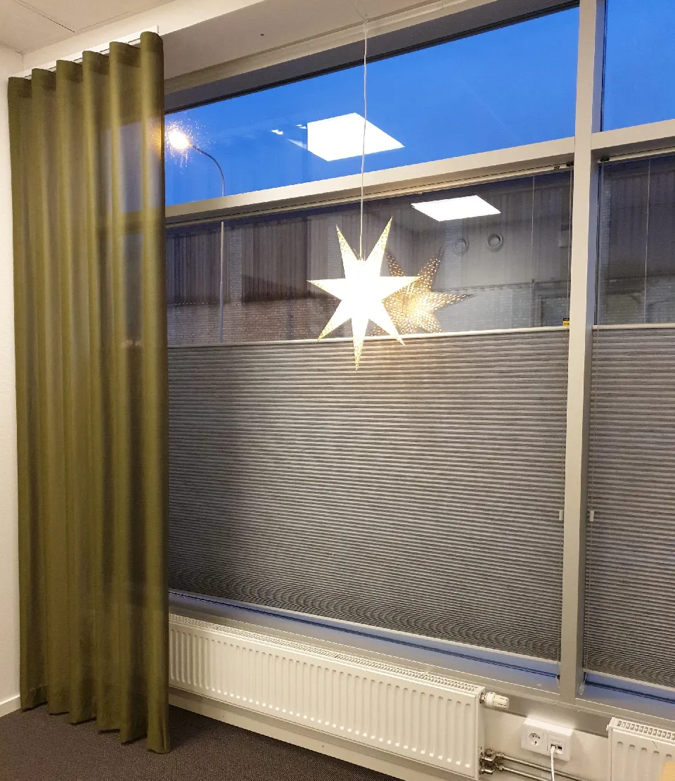 Adventsstjärna i ett fönster bakom en gardin