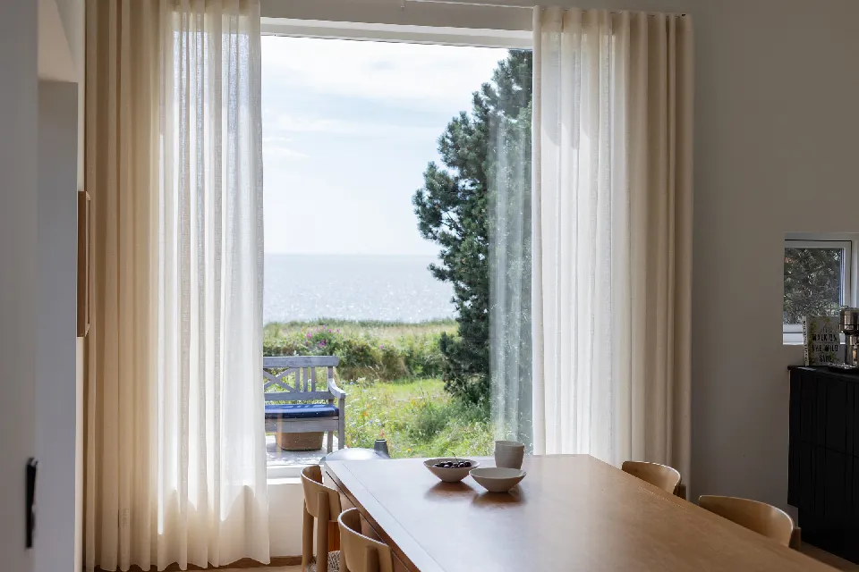 Skira gardiner vid matbord med havsutsikt